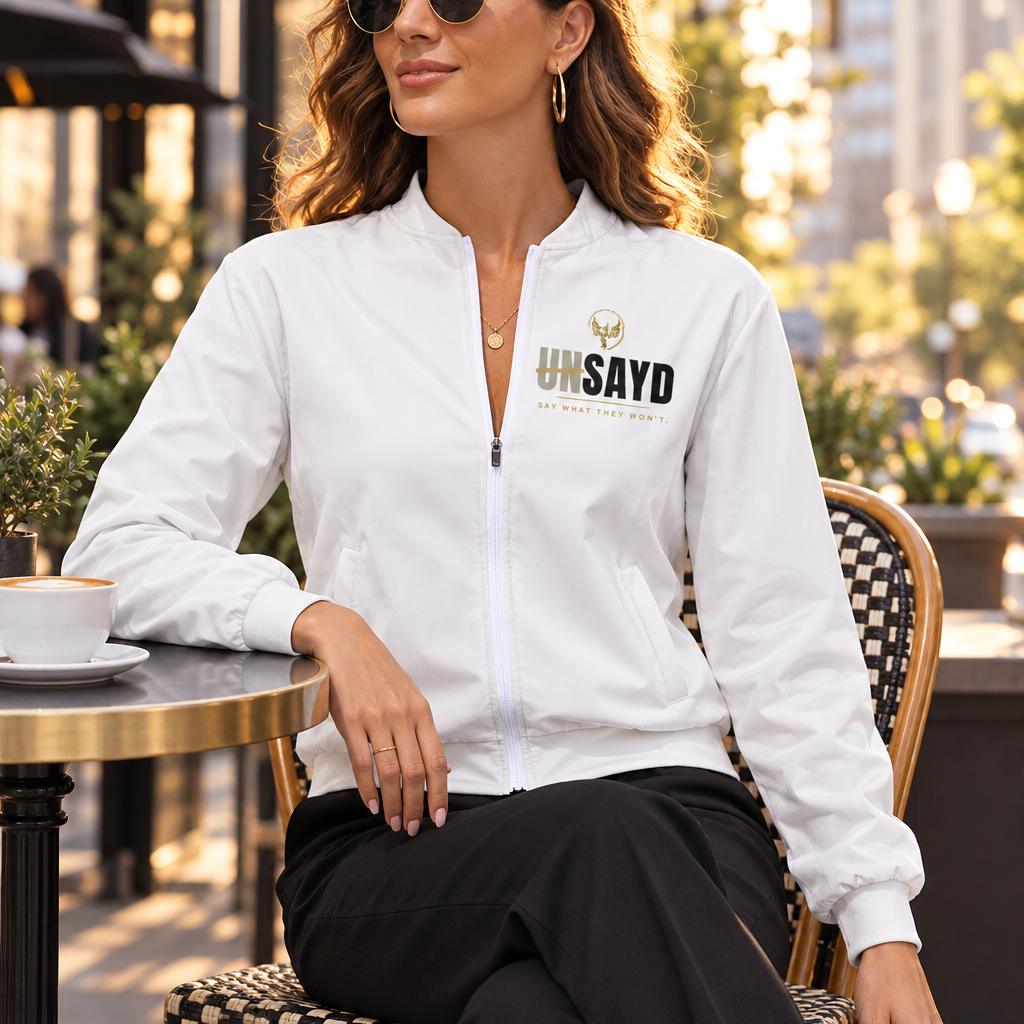 Woman wearing white UNSAYD zip jacket at a downtown café terrace